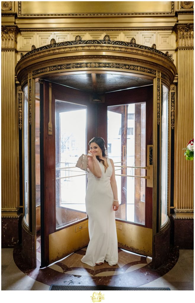 A bride holds her shoes at her Hartford City Hall Spring elopement, in Hartford CT